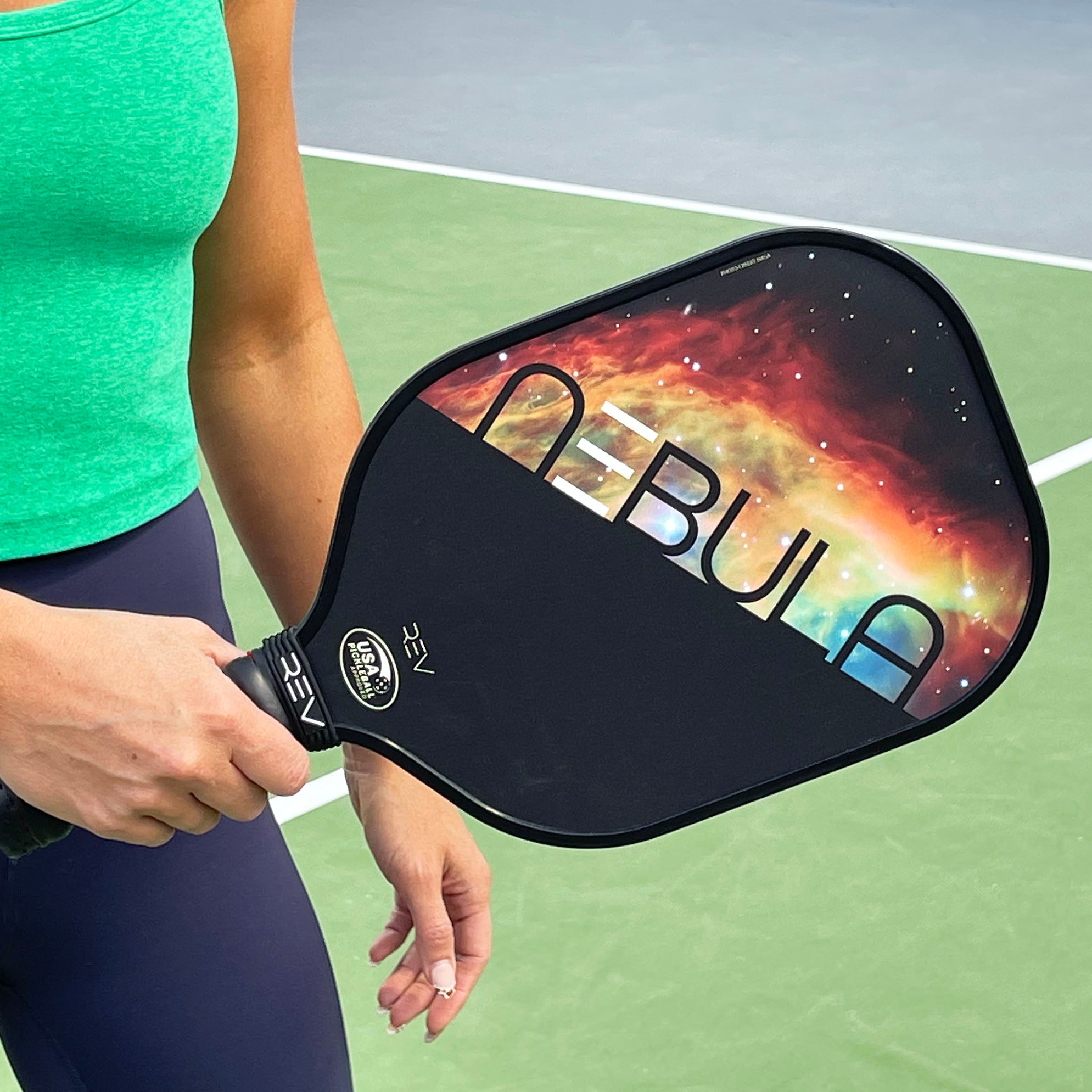 Close-up of a player gripping the USAPA-approved REV NEBULA pickleball paddle on the court